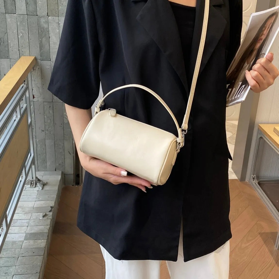 Brown cylindrical leather crossbody phone bag with visible stitching on a flat surface.