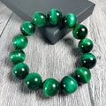 Green tiger eye stone bead bracelet with geometric polished beads on a wrist.