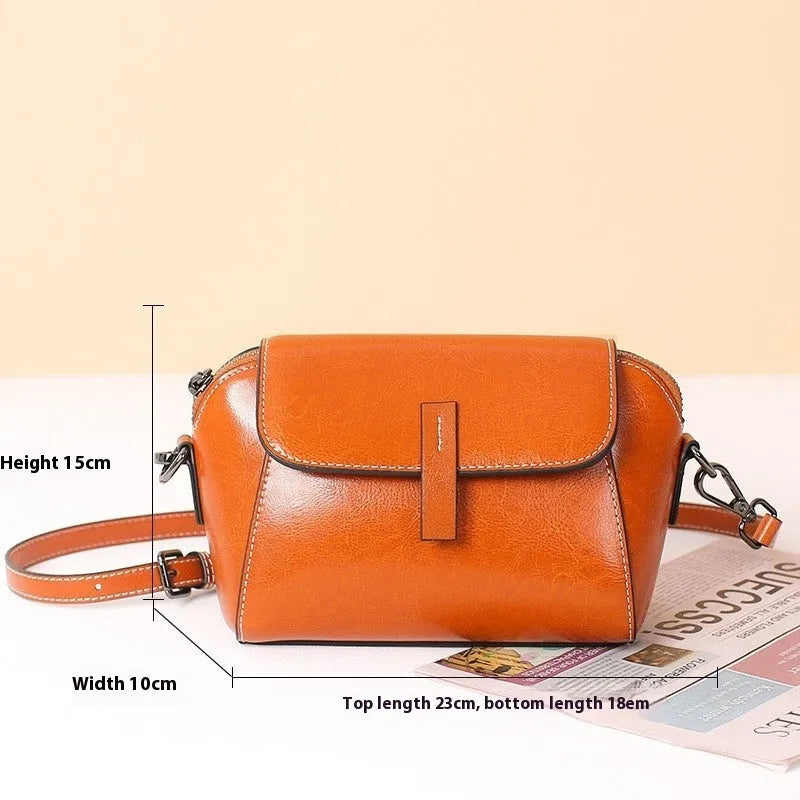 Brown women's shell-shaped genuine leather messenger bag with a single cross-body strap and visible stitching.