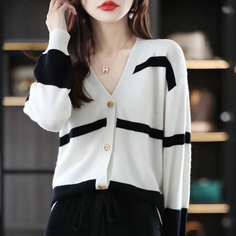 A woman wearing a slim-fit black and white striped V-neck knitted cardigan.