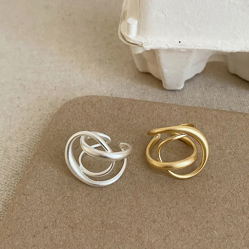 Geometric open ring for women with a three-dimensional interlaced design in matte metal.
