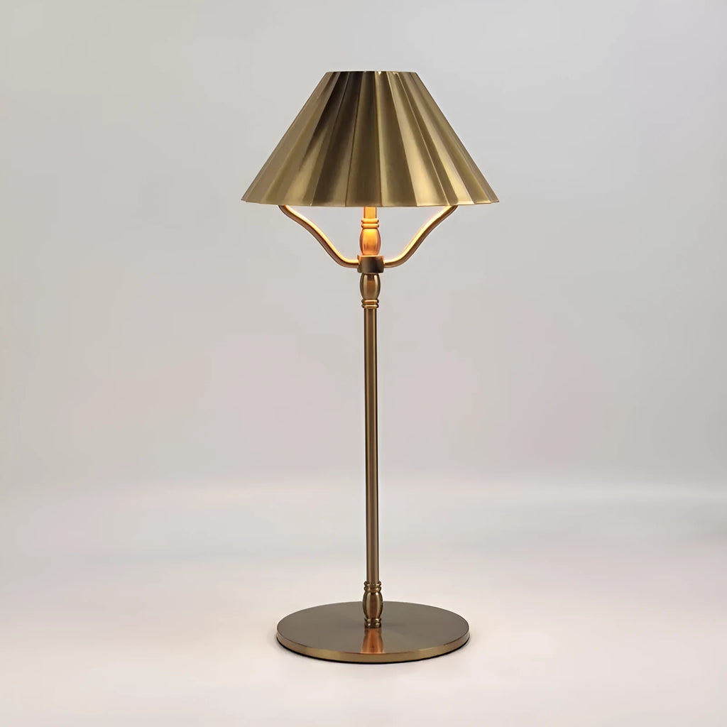 Gold-colour alloy desk lamp with a cylindrical shade on a wooden desk, showing a USB-C charging cable.
