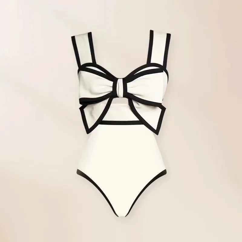 Women's black one-piece swimsuit with a white flared skirt and a central bow detail.