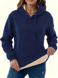 Woman wearing a thick grey hooded sweater with a 3D pattern and front pockets