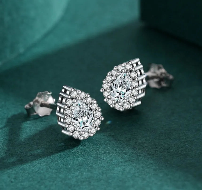 Close-up of a pair of women's silver water drop shaped stud earrings on a plain background.