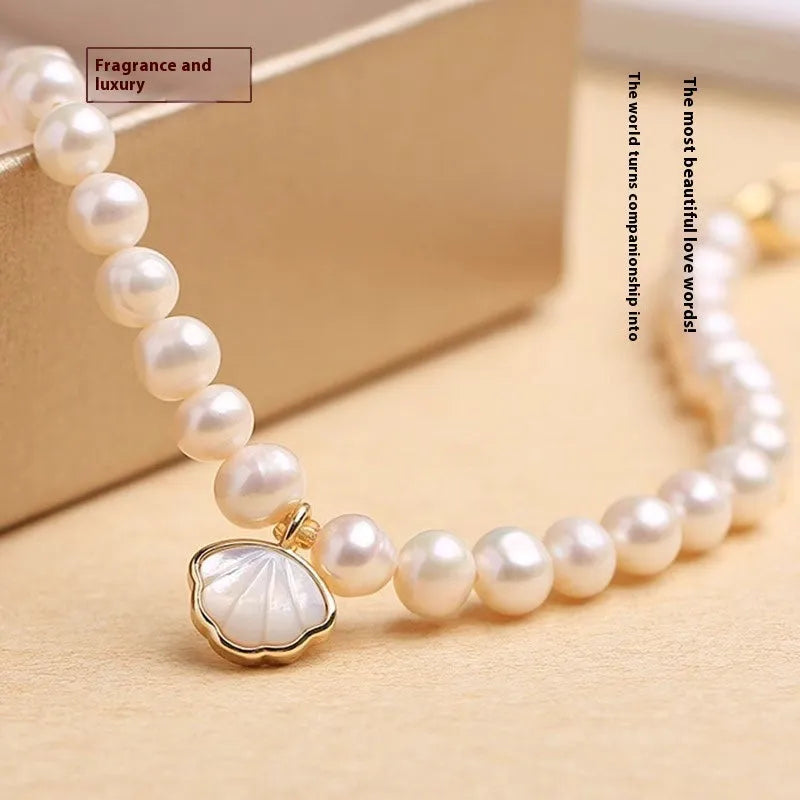 Women's freshwater pearl bracelet with a fan-shaped shell on a wrist, showing elastic and extension chain fastening options.