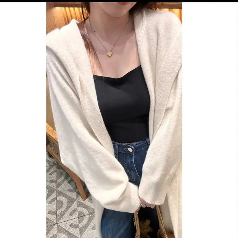 A woman wearing a long, hooded, beige knitted cardigan in a relaxed Korean style.