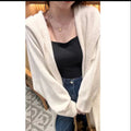 A woman wearing a long, hooded, beige knitted cardigan in a relaxed Korean style.