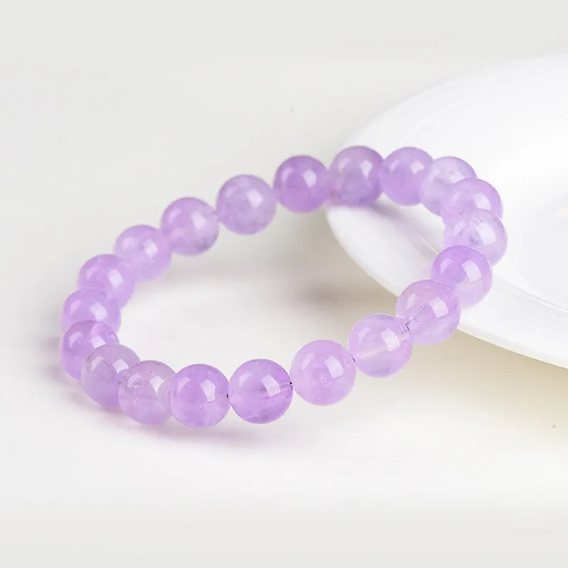 Lavender round amethyst bead bracelet with water ripple design on a wrist.