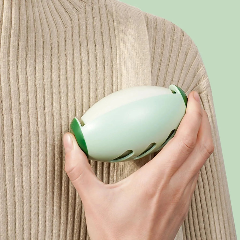 Green washable reusable gel lint roller ball for pet hair removal on a blue sweater.