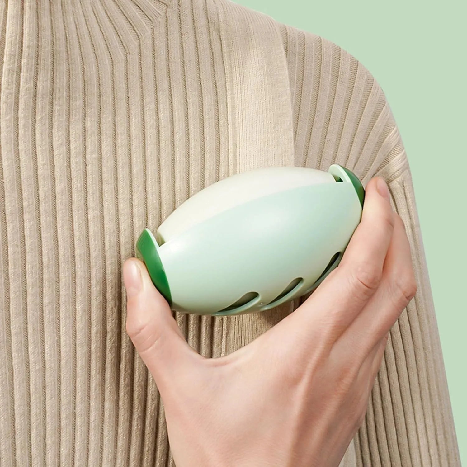 Green washable reusable gel lint roller ball for pet hair removal on a blue sweater.