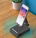 Black mobile phone broadcasting stand with integrated Bluetooth speaker on a desk.