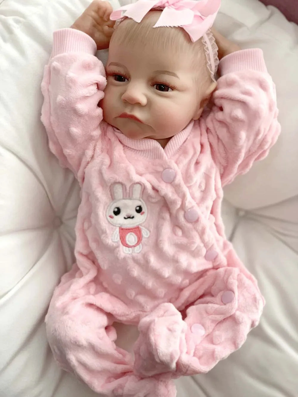 18-inch reborn doll with cloth body in soft pink romper sitting on table