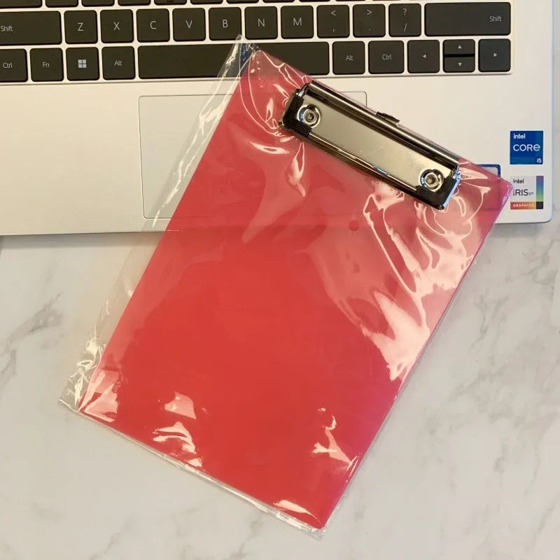 Transparent A4 plate holder with metal clip in blue, holding white paper, on a wooden desk.