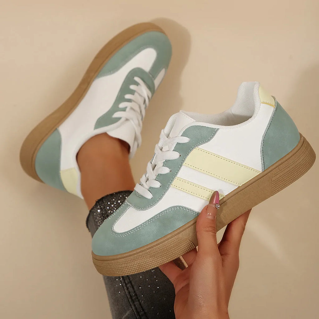 Green women's retro sports shoes with white cross-strap detail and leather stitching on a low rubber sole.