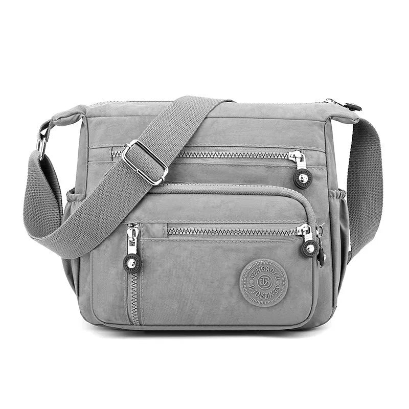 Soft nylon messenger bag in square vertical shape with an adjustable shoulder strap.