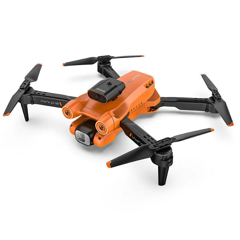 Black quadcopter drone with camera folded on a surface next to its remote control.