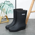 Women's mid-calf PVC rain boots in black with low heel, shown in short tube design