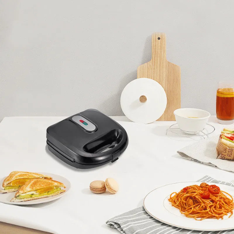 Black double-sided electric sandwich pan with stainless steel lid on a kitchen counter