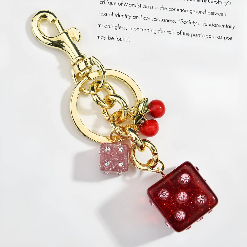 Close-up of a square metal keychain pendant with a two-tone red cherry dice pattern.