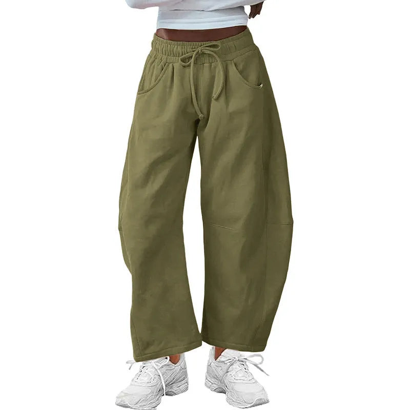 Woman wearing loose grey cropped sweatpants with drawstring waist and side pockets, street fashion style.