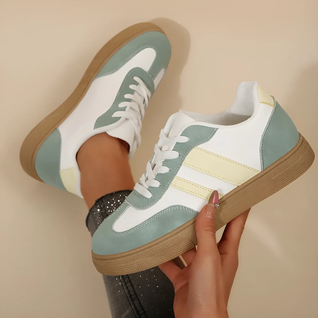 Green women's retro sports shoes with white cross-strap detail and leather stitching on a low rubber sole.