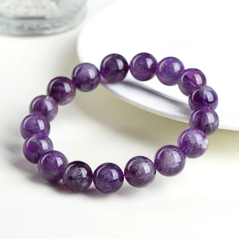 Natural feather amethyst purple crystal bracelet with geometric beads and Ruyi symbol on a white background.