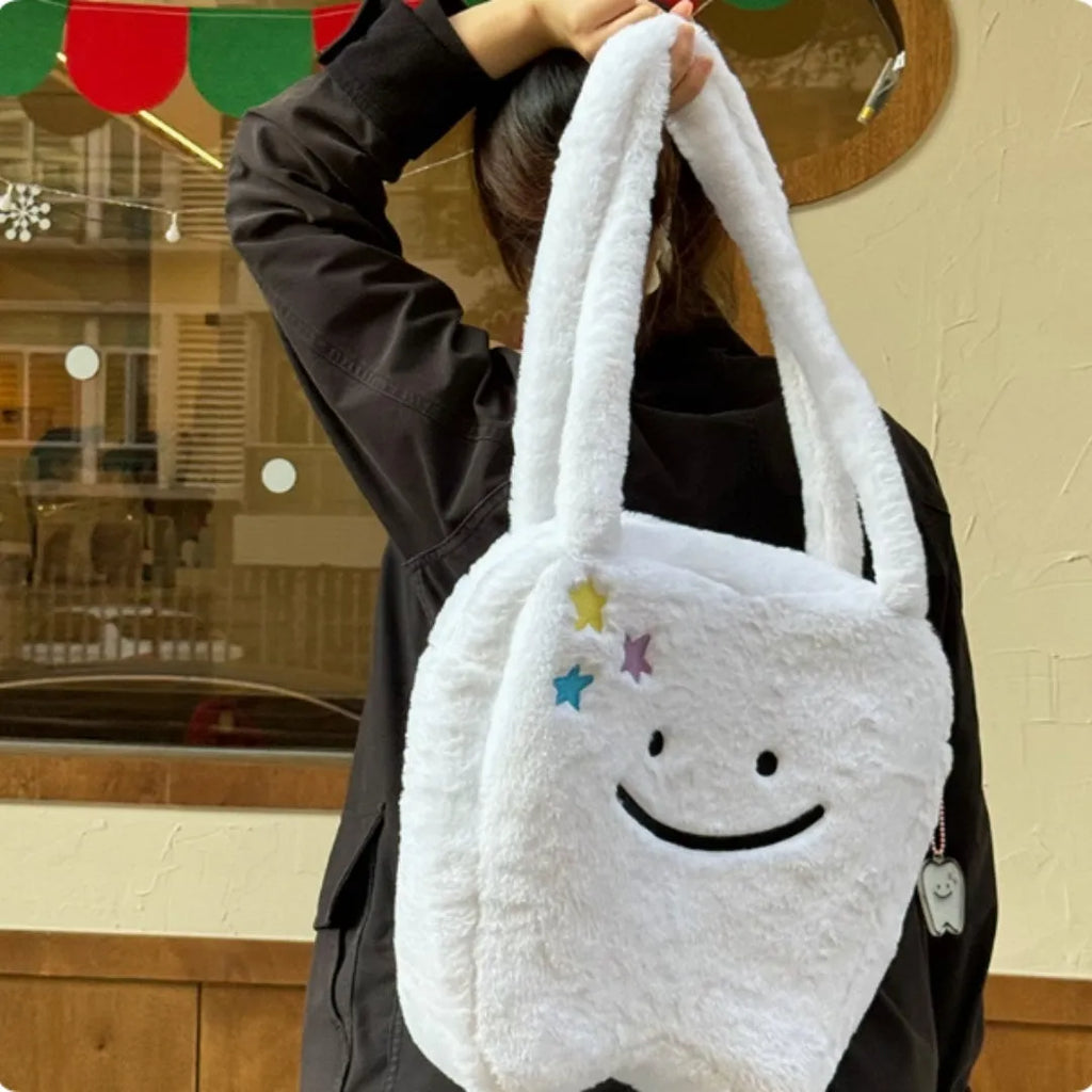White plush tote bag with large cute teeth graphic, showing crossbody strap and zip opening.