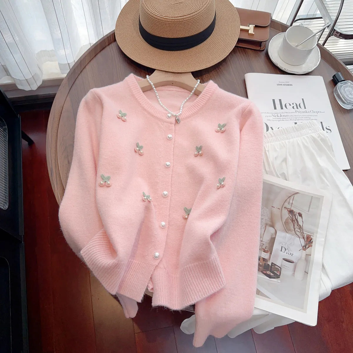 Women's slim fit cashmere cardigan with bead details on hanger, showing gentle round neckline in pink colour.