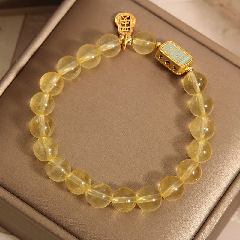 Women's bracelet with yellow citrine stones and sparkling rhinestone details on a white background.