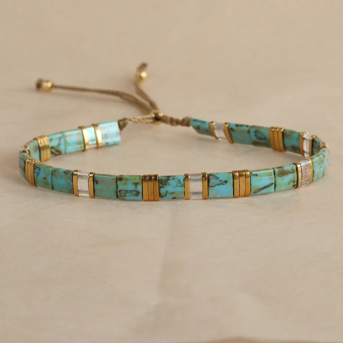 Geometric glass bead bracelet with pull beads design on a wrist, shown in milky white colour.