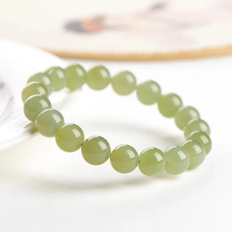 Polished Hetian Jade ball bracelet in clear water colour on a wrist, showing multiple bead sizes.