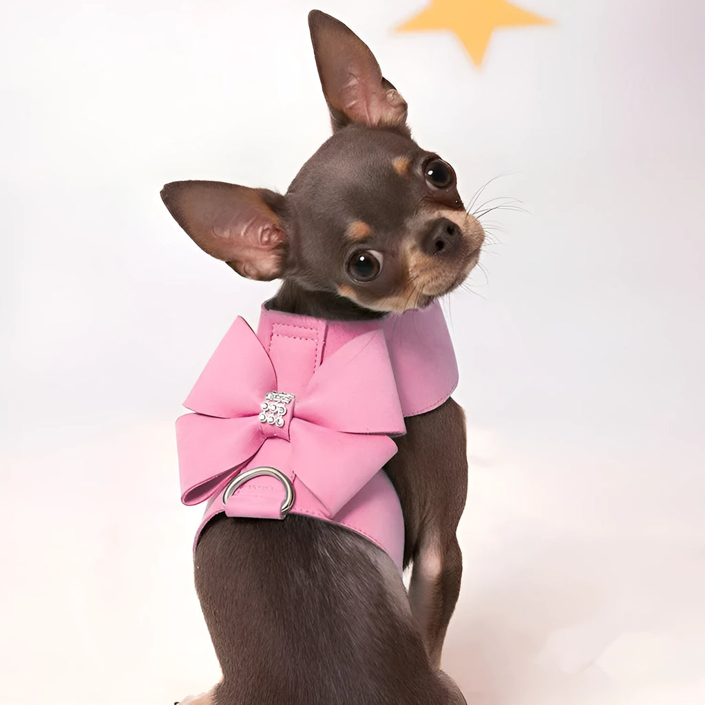 A pink microfiber dog chest strap with a large decorative bowknot, showing leash attachment ring.