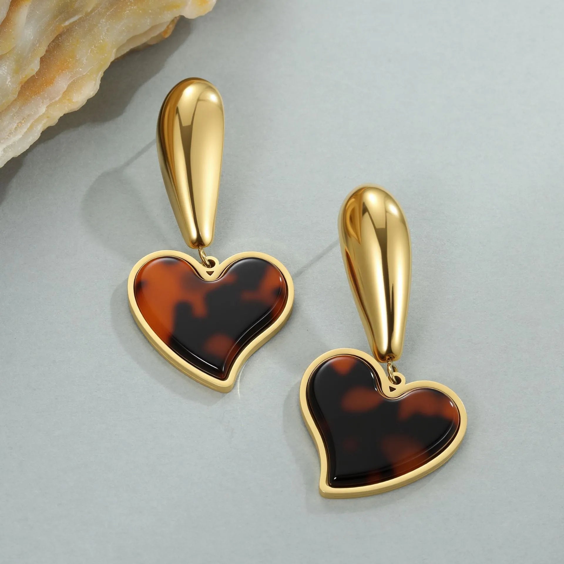 Close up of 18K gold plated stainless steel earrings featuring tortoiseshell resin in heart and flower geometric shapes for women.