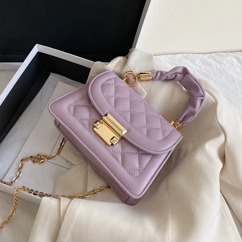 A purple PU leather small square women's crossbody bag with a chain detail and a long strap.