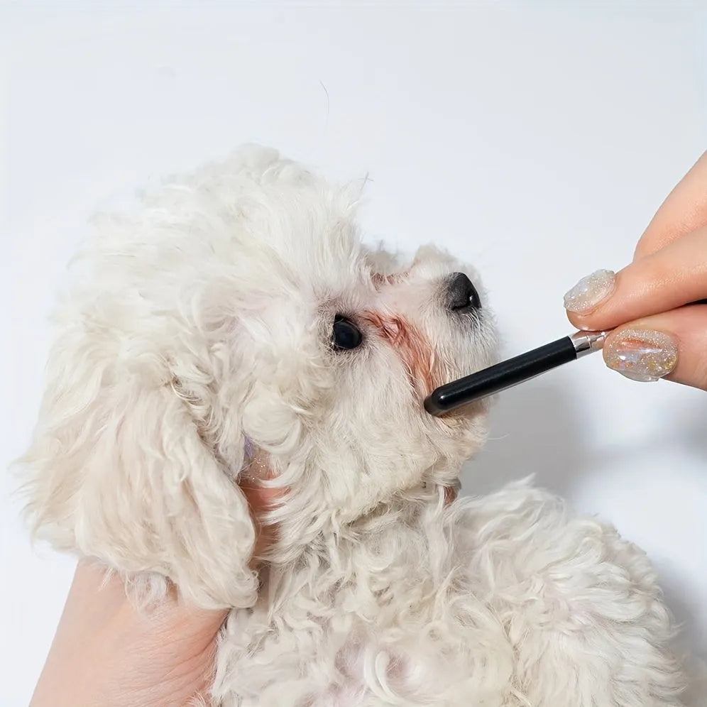 Black pet grooming brush with soft silicone bristles for eye cleaning and comb attachment for hair removal