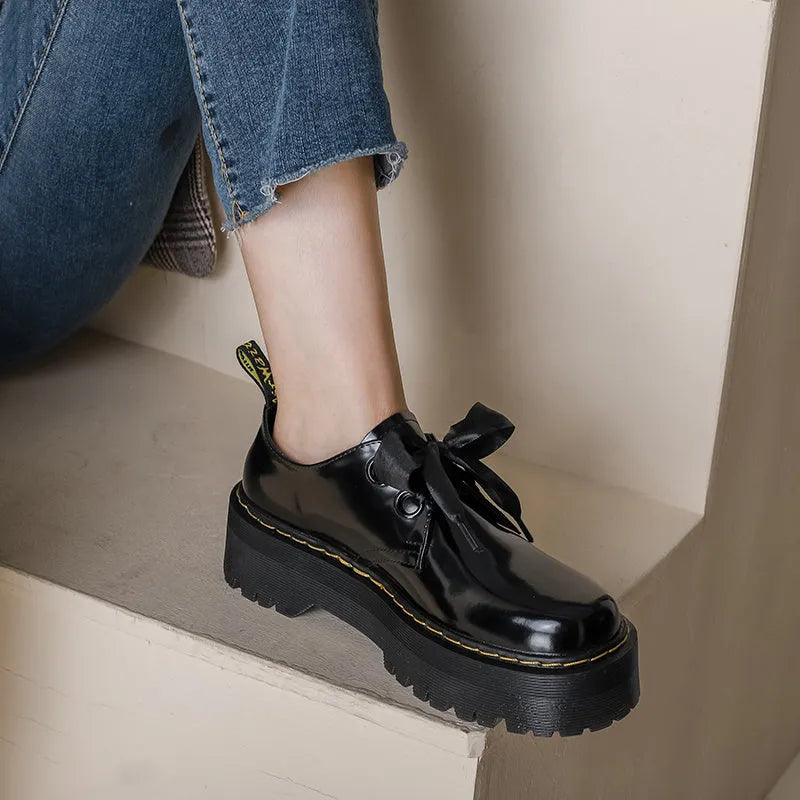 Women's white and black leather shoes with thick soles, ribbon and cross-strap design, and laced closure.
