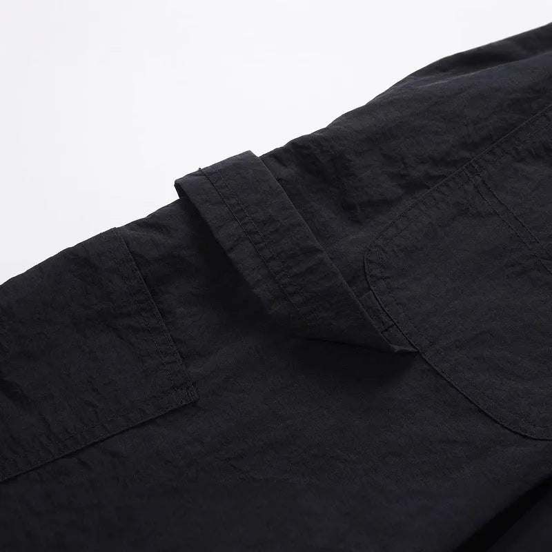 Men's black baggy paratrooper pants with a drawstring waist on a neutral background.