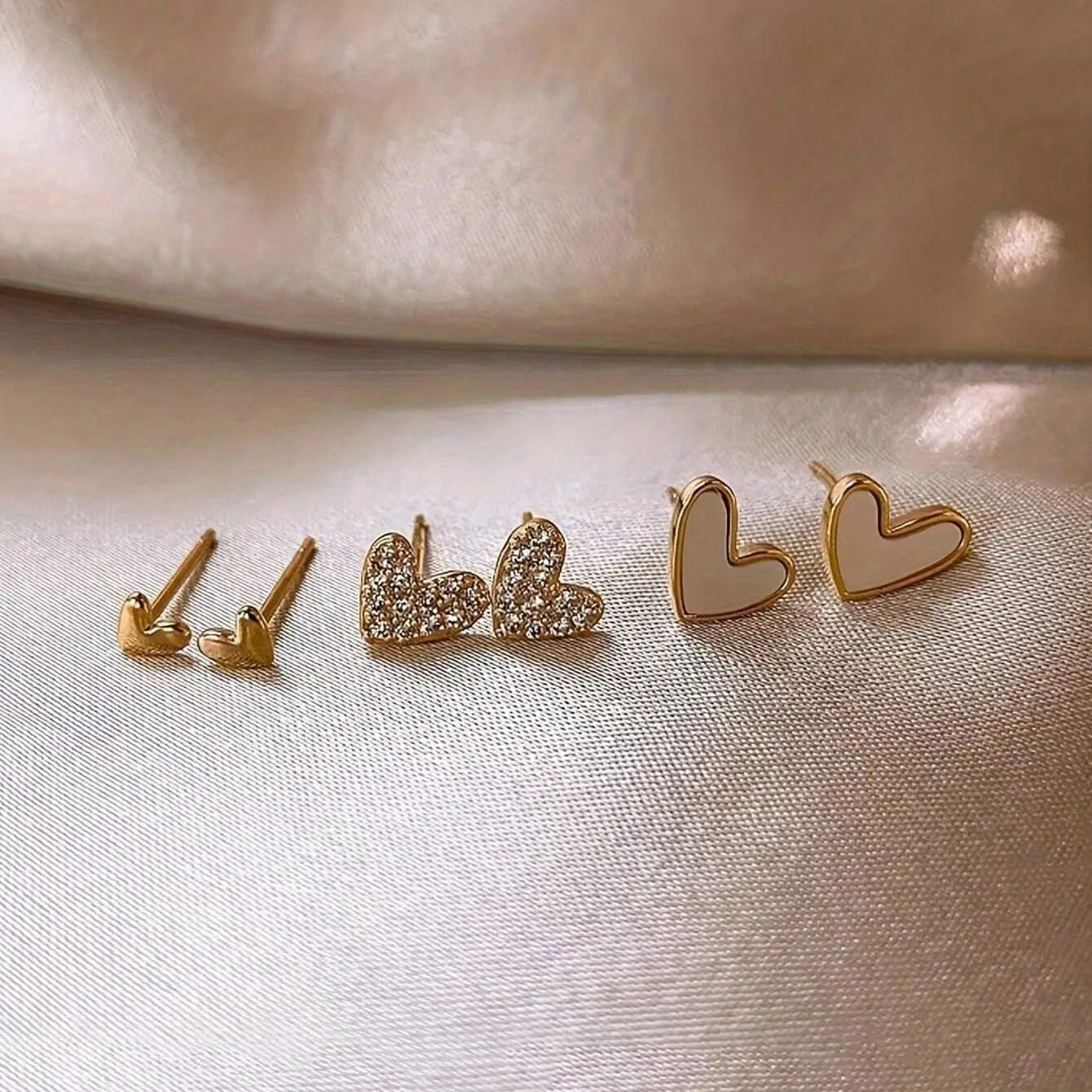Three pairs of women's heart-shaped alloy earrings in electroplated gold, black, black-white, or pink colours