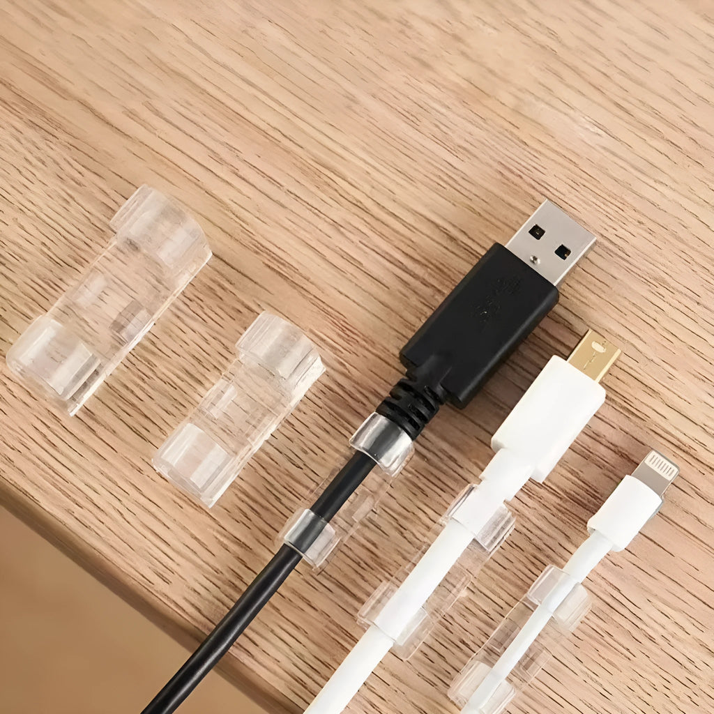 Transparent plastic self-adhesive cable clips for wire management on a desk.