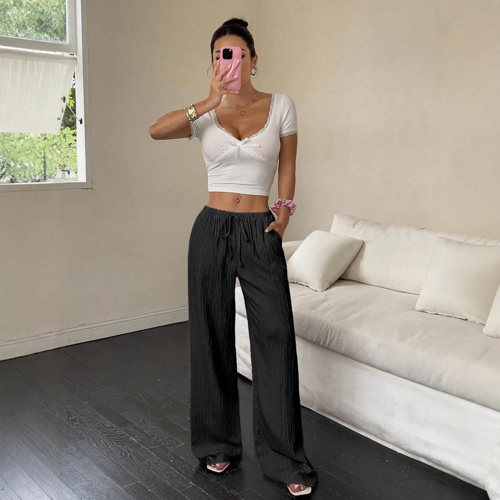 Women's black wide leg trousers with lace-up waist trimming showing adjustable detail