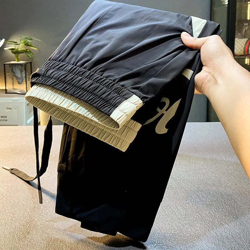 Men's black cropped ankle band trousers in ultra-thin ice silk cotton material showing casual styling