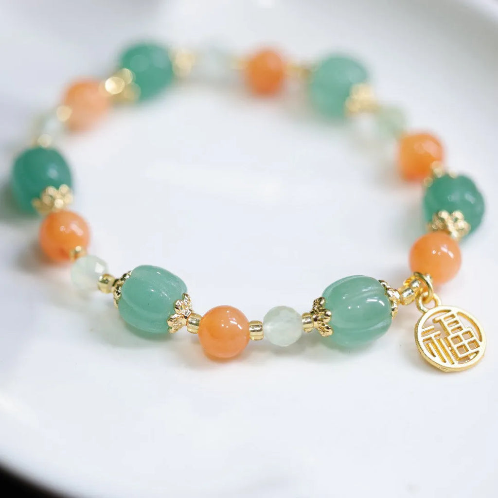 Jinsi Jade Duobao pumpkin bracelet with Prehnite bead on a flat surface, showing carved pumpkin bead and spacer beads