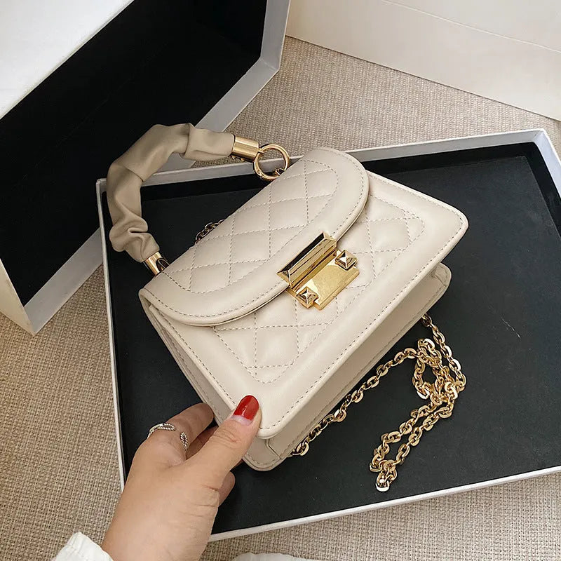 A purple PU leather small square women's crossbody bag with a chain detail and a long strap.