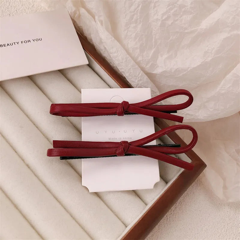 Wine red leather bow hair barrettes showing front and back views
