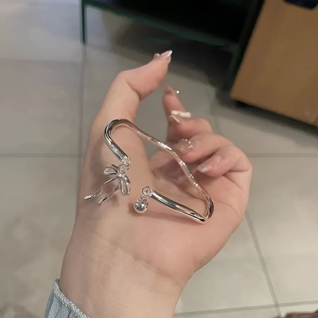 Silver bow adjustable bracelet with bow bell opening clasp on wrist