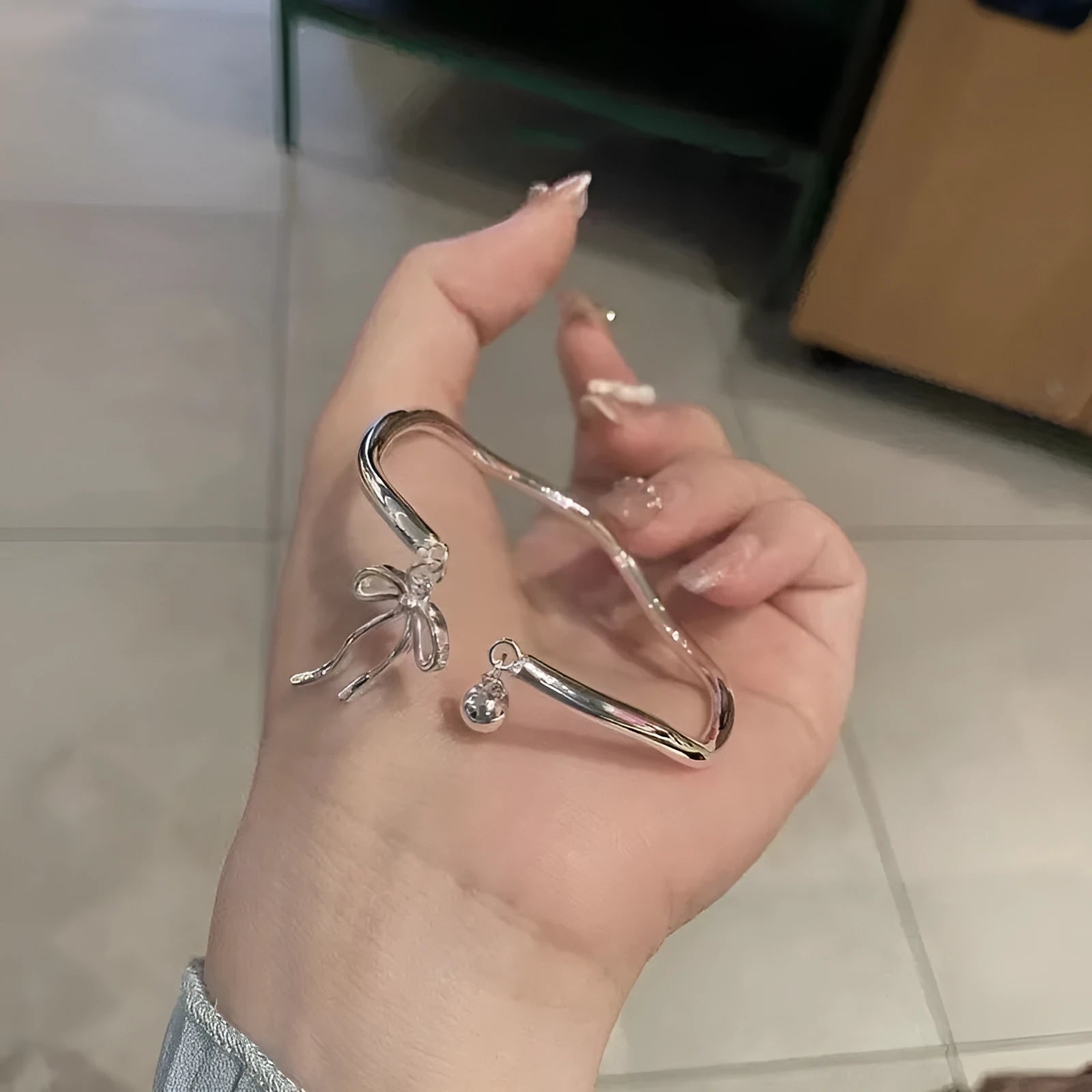 Silver bow adjustable bracelet with bow bell opening clasp on wrist