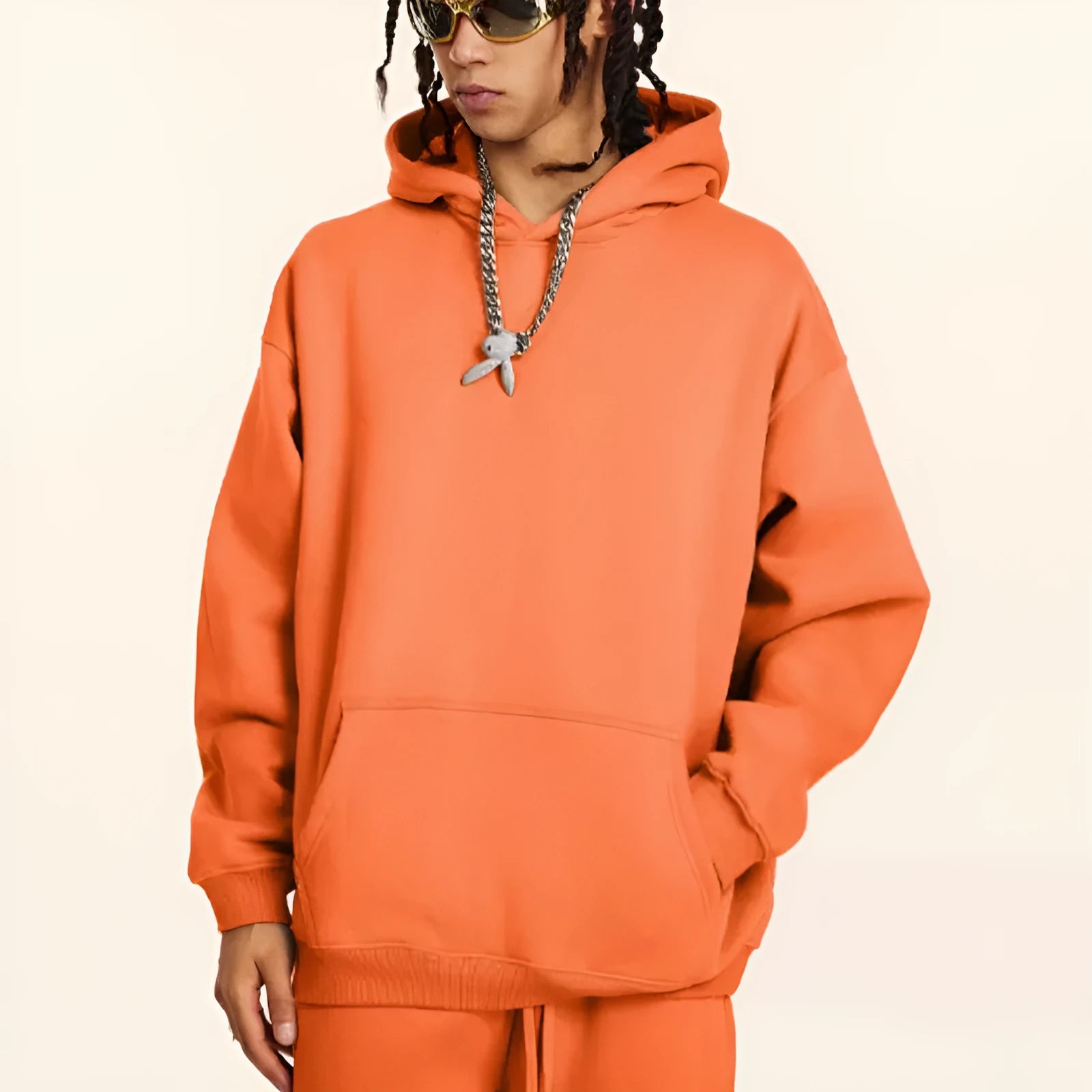 Man wearing a loose grey cotton terry hooded sweater with drop-shoulder sleeves.