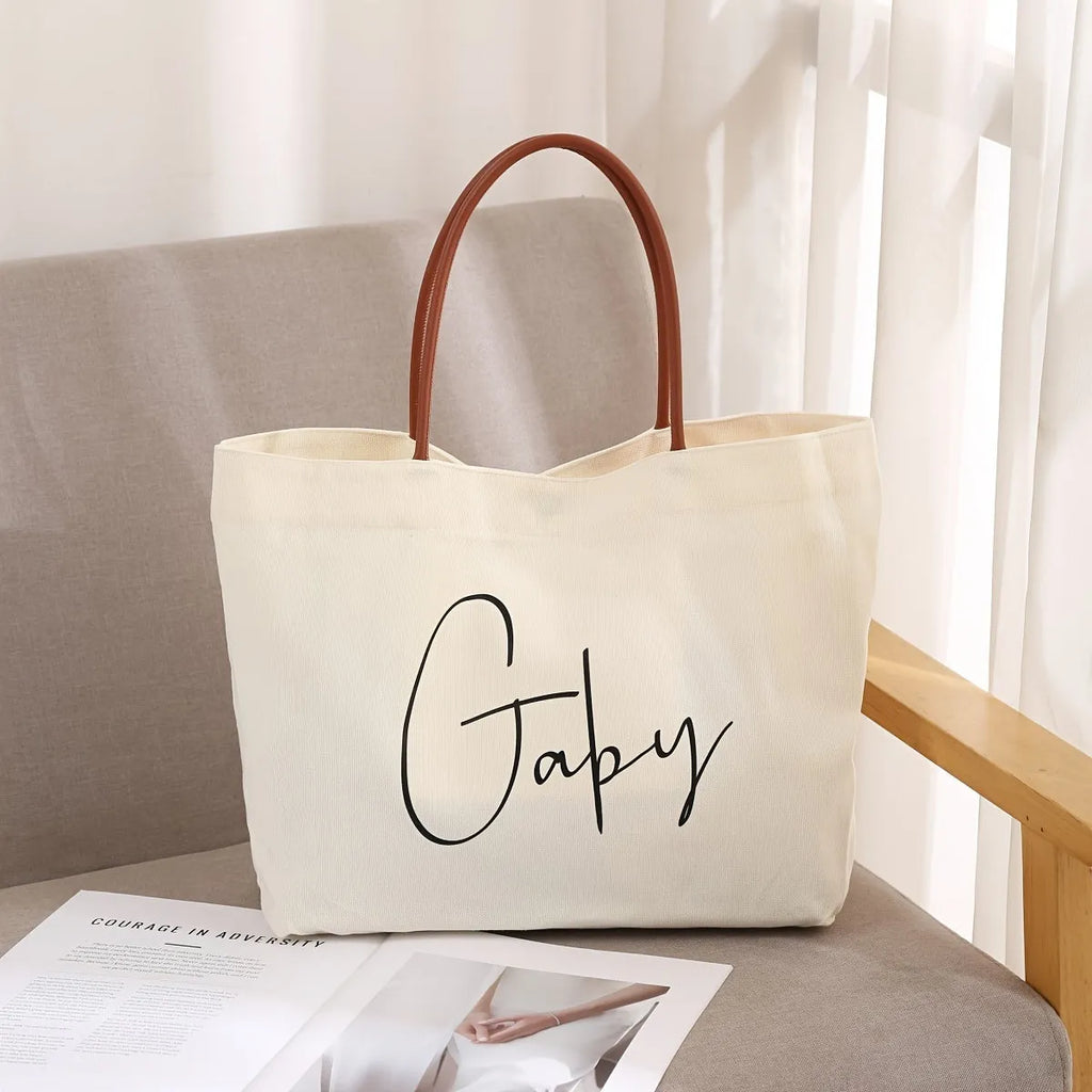 Beige white canvas tote bag with a front zip pocket and sturdy shoulder straps laid flat.