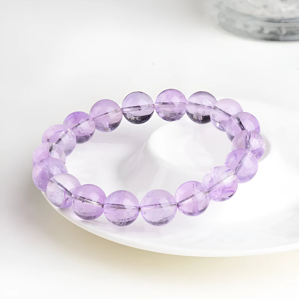 Lavender round amethyst bead bracelet with water ripple design on a wrist.